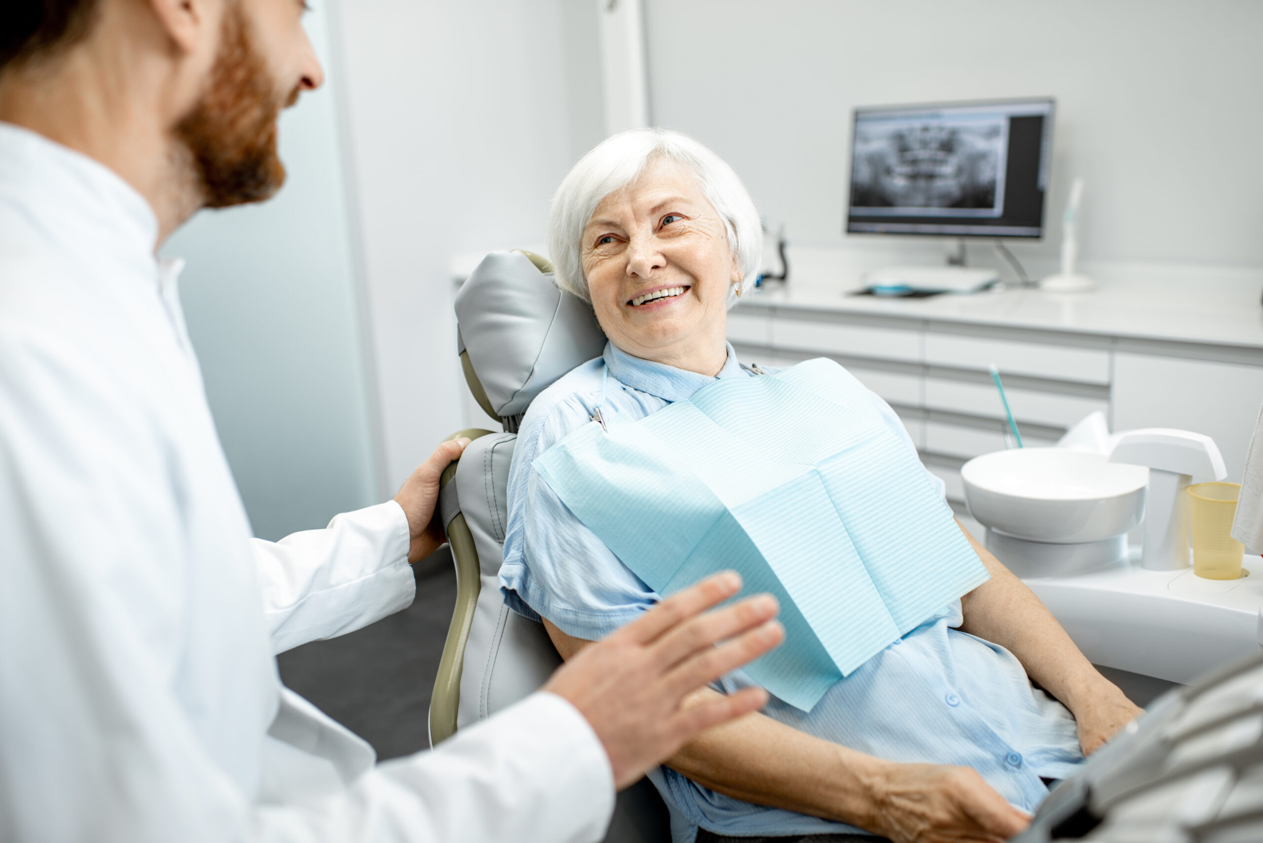 elderly woman smiling at the dentist wearing her dentures