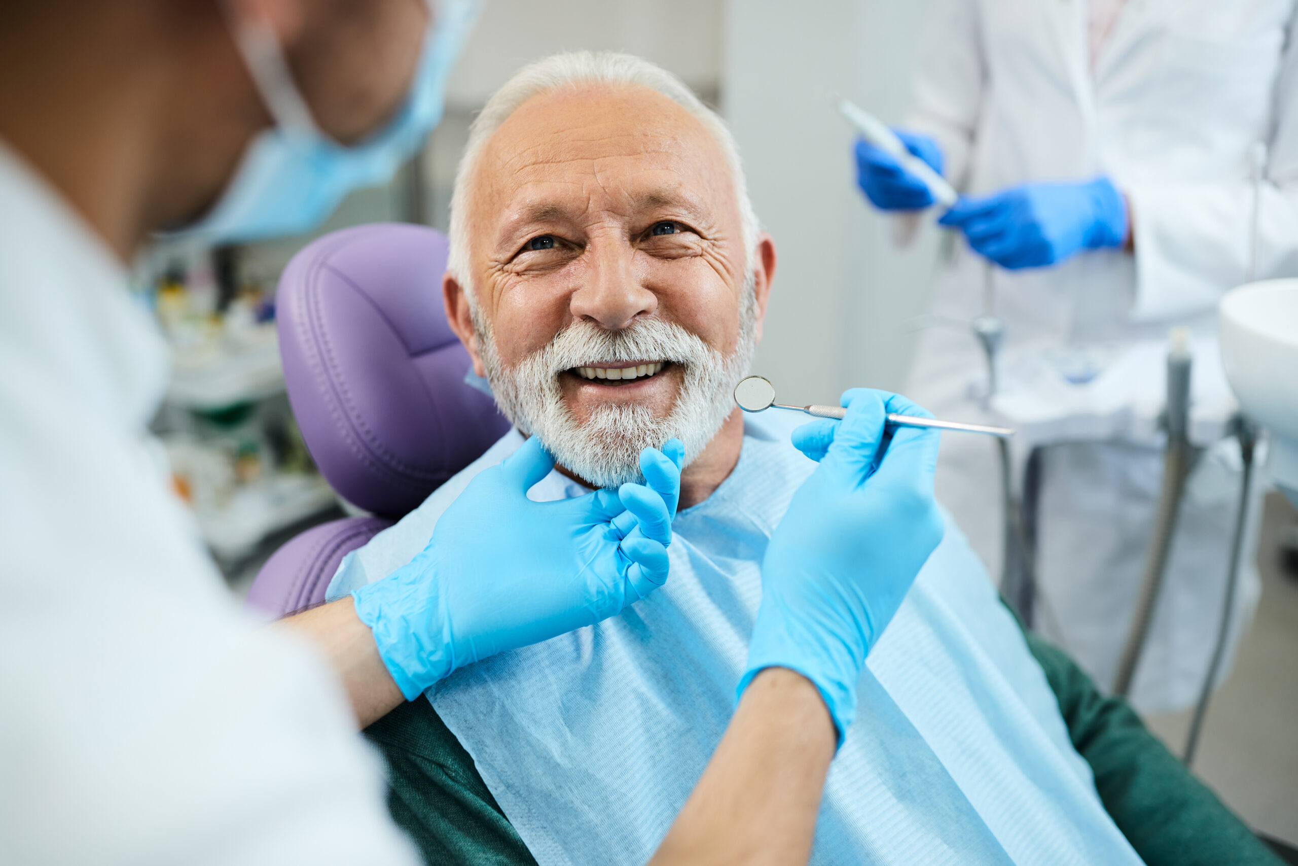 elderly man smiling at the dentist wearing her dentures