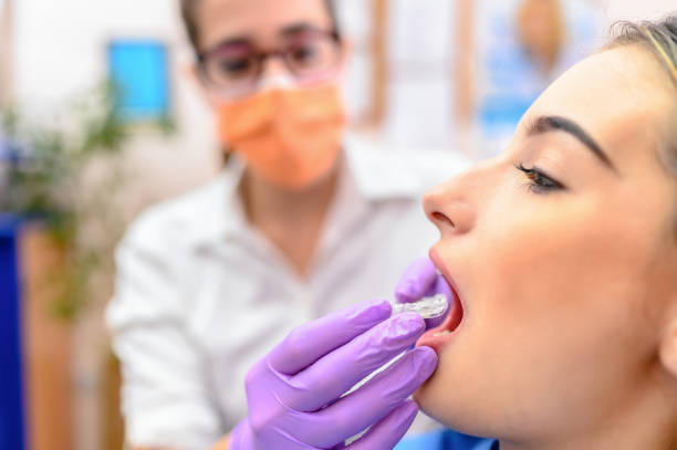 Dentist hand showing an implant to a patient in an office